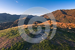 Hiker staring at the far away beauty of the Lake Wanaka in New Zealand under the morning sun during golden hour time