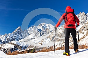 Hiker takes a rest looking at Mont Blanc panorama during the famous winter trekking Tour du Mont Blanc. Mont