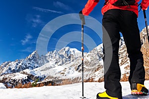 Hiker takes a rest looking at Mont Blanc panorama during the famous winter trekking Tour du Mont Blanc. Mont