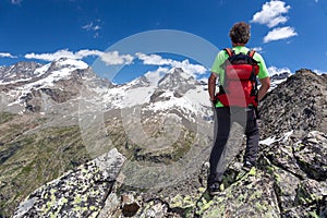 A hiker takes a rest looking at mountain panorama. Gran Paradiso National Park, West Alps, Val d`Aosta, Italy