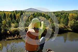 Hiker taking photo with smartphone at the riverside mountain