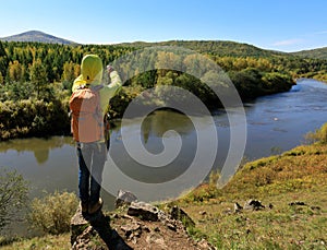 Hiker taking photo with smartphone at the riverside mountain