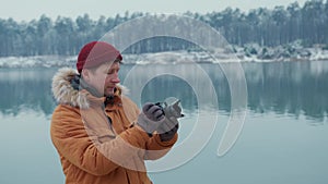 Hiker taking pictures of snowy nature in winter Lake background winter forest.