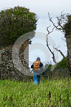 Hiker at threshold between isolated ruins of medieval Carrigaholt Castle, Ireland, and panoramic view beyond the tower wall.