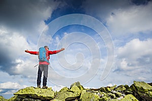 Hiker at the top of a rock with backpack enjoy sunny day