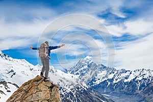 Hiker at the top of a rock with his hands raised enjoy sunny day