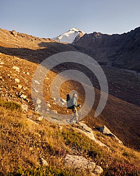 Hiker tourist with backpack at mountain valley at sunset