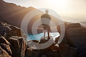 Hiker tourist looking at mountain lake at sunset