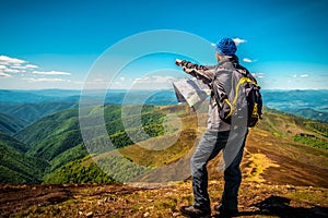 Hiker tourist man with map in summer mountains