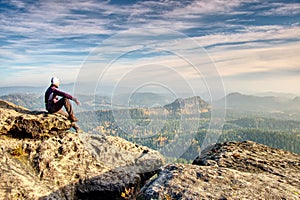 Hiker in trekking clothes sit alone on rock summit. Wonderful daybreak in mountains