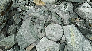 A hiker with trekking poles walks on rocks and boulders. A first-person view