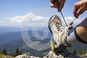 Hiker tying boot laces, high in the mountains