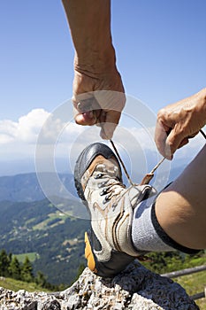 Hiker tying boot laces, high in the mountains