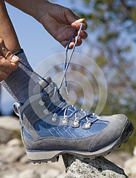 Hiker tying boot laces, high in the mountains