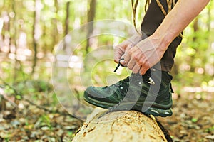 Hiker tying boot laces on a log