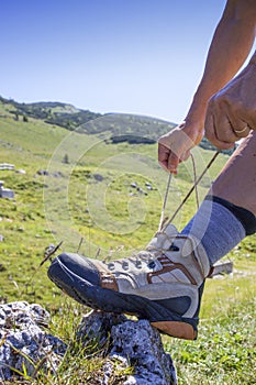 Hiker tying boot laces, high in the mountains