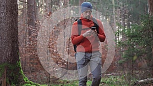 Hiker using mobile application to navigate in fall forest. Pathfinder tries to find best way in woods. Active lifestyle