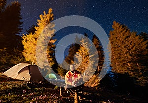 Hiker vacationing on nature in tent camp under starry sky.