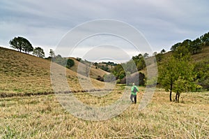 Hiker in a valley between small hills under dark clouds