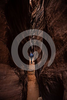 Hiker Walking Through High Walled Slot Canyon