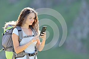 Hiker walking using phone in the mountain