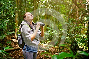 Hiker watching through binoculars wild birds in the jungle. photo