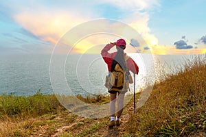 Hiker woman climb up the last section of sunset in mountains near the sea. Traveler walking in outdoor