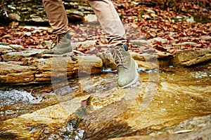 Hiker woman crossing a stream, view of legs