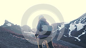 hiker woman hiking on the rocks in the mountains in a cold day in spring or summer. Backlit sun light at sunset or
