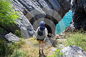 Hiker woman look binoculars on the sea, background blue sky,