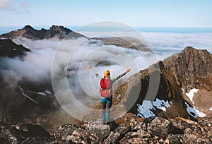 Hiker woman raised hands on mountain summit above clouds travel hiking with backpack outdoor