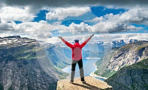 Hiker woman standing with hands up achieving the top. Amazing nature view on the way to Trolltunga. Location: Scandinavian