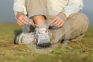 Hiker woman tying shoelaces of boots photo