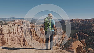 Hiker Woman Walking To Edge Of Rocks On Top And Raises Her Hands Up Success