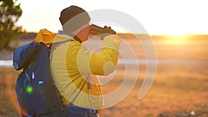 Hiker young tourist enjoying nature, drinking hot tea at sunset. Traveler young man drinking hot tea from stainless