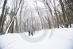 Hikers with backpack hiking on snowy trail. Group of people walking together at winter day