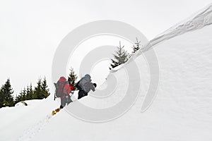 Hikers climbing in a deep snow high in the winter mountains