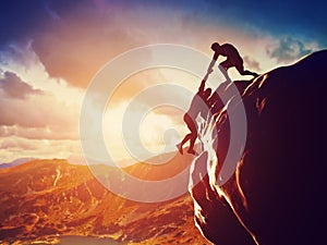 Hikers climbing on rock, giving hand and helping to climb photo