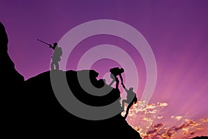 Hikers climbing on rock, mountain at sunset, one of them giving hand and helping to climb.Teamwork , Helps ,Success, winner and Le