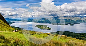 Hikers descending Conic Hill towards Loch Lomond with beautiful mountain scenery