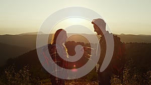 Hikers enjoying hike in mountains at sunset. Man proposing marriage to woman