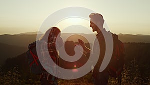 Hikers enjoying hike in mountains at sunset. Man proposing marriage to woman