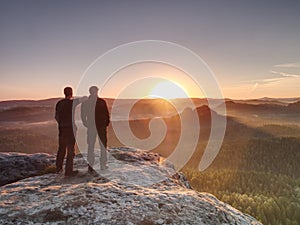 Hikers and friends on cliff within dreamy daybreak and thinking