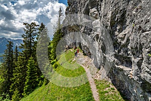 Turisté na turistické stezce pod mohutnou skálou v Nízkých Tatrách, Slovensko