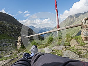 Hikers legs, foot in rubber clogs relaxing at view from Nurnberger Hutte hut, valley with mountain peaks at Stubai photo