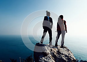 Hikers looking at the view on seaside mountain top rock edge