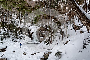 Hikers near frozen Kinsman Falls in Franconia Notch State Park during winter . New Hampshire mountains. USA photo