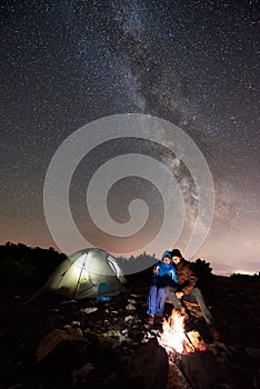 Hikers resting at night camp in mountains under starry sky