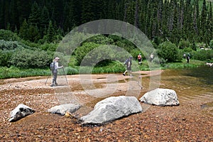 Hikers in shallow water on Hassell Lake Trail in Arapaho Nat'l Forest, Colorado.