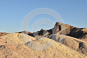 Hikers stand on a peak at Zabriskie Point